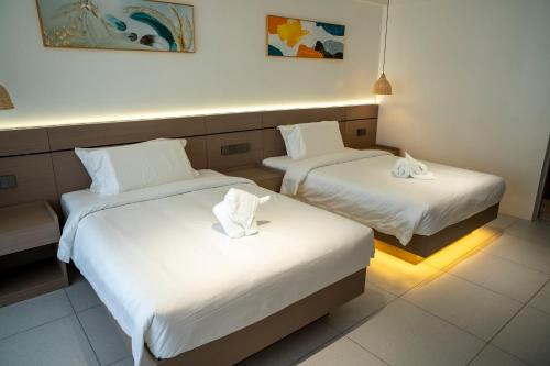 two beds in a hotel room with white sheets at Willander Resort in Panglao Island