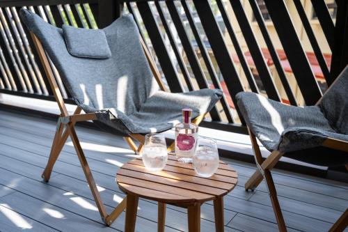 two chairs and a bottle of wine on a table on a porch at Tanuki Nozawa in Nozawa Onsen