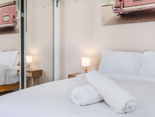 a bedroom with a white bed and a mirror at Hastings Cove Holiday Apartments in Hastings Point