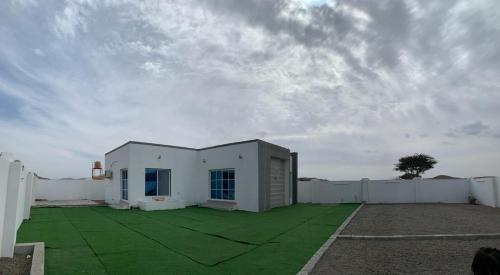 a white building with a green lawn in front of it at بيت الضيافه للتواصل98423336 in Ibrā