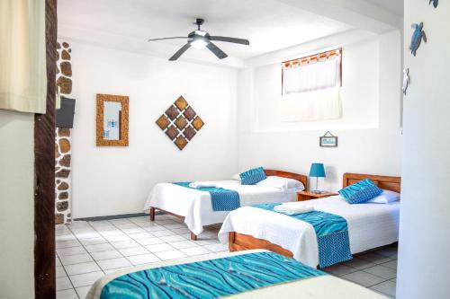 a room with three beds and a ceiling fan at Maidith Galapagos Inn in Puerto Ayora