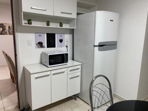 a kitchen with a white refrigerator and a microwave at Apartamento até 8 pessoas Araxá Ótima localização in Araxá
