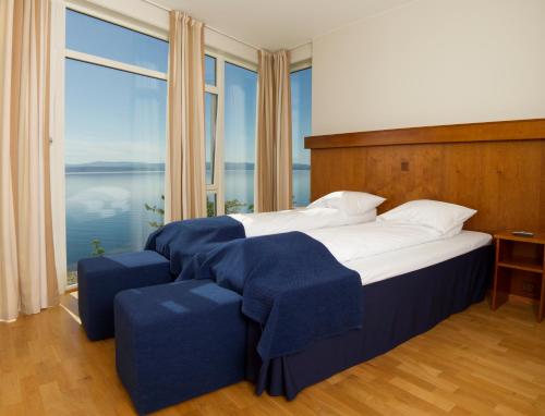 a bedroom with a large bed with blue covers at Jegtvolden Fjordhotell in Straumen