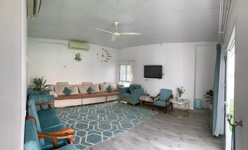 sala de estar con sofá, sillas y TV en بيت الضيافه98423336, en Ibrā
