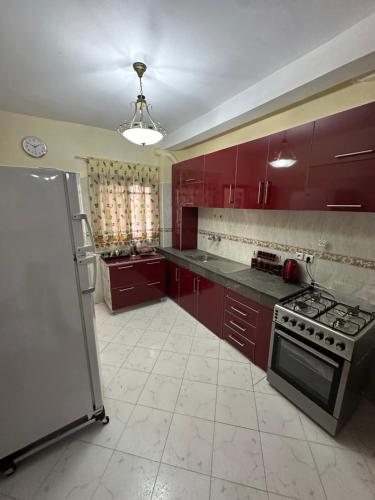 La cuisine est équipée de placards rouges et d'un four avec plaques de cuisson. dans l'établissement Tranquility In the Center of Fez, à Fès