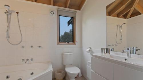 a bathroom with a tub and a toilet and a sink at Powderkeg in Dinner Plain