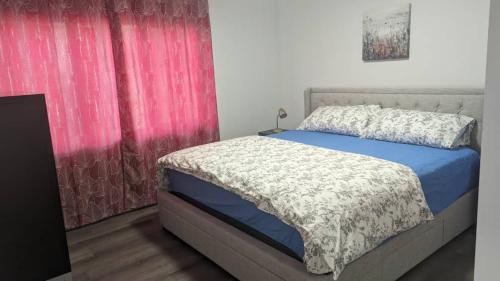 a bedroom with a bed and a pink curtain at Comfy one bedroom Airdrie in Airdrie