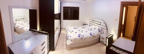ein weißes Schlafzimmer mit 2 Betten und einem Spiegel in der Unterkunft Um Uthaina Place in Amman