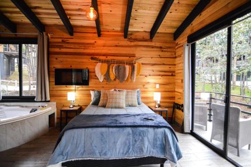 een slaapkamer met een bed, een bad en ramen bij Cabaña Citrus para parejas in Mazamitla