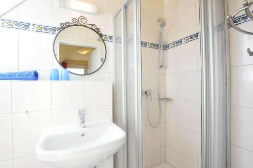 a bathroom with a sink and a shower with a mirror at Ferienwohnung-Min-Droom in Sankt Peter-Ording
