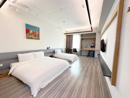 um quarto de hotel com uma grande cama branca e uma secretária em Thinker Hotel em Yingge