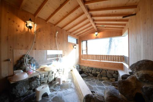 Zimmer mit einem Bad mit einer Steinmauer in der Unterkunft のんびれっじ　ハイランド館 in Nasu