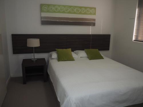 マンジュラにあるLovely 2 Bedroom Serviced Apartment & Free Parkingの緑の枕が付いた大きな白いベッドのある寝室