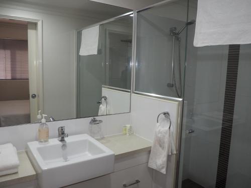 a white bathroom with a sink and a shower at Lovely 2 Bedroom Serviced Apartment & Free Parking in Mandurah