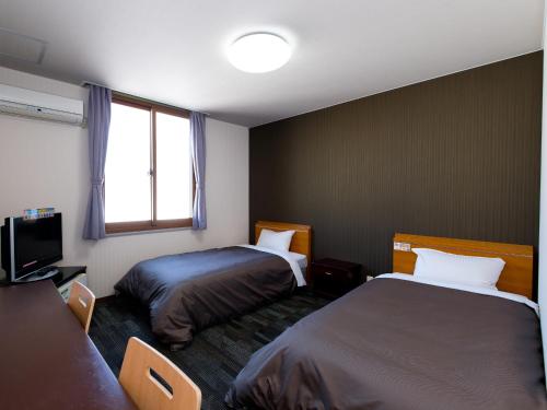 松山市にある松山ニューグランドホテルのベッド2台と窓が備わるホテルルームです。
