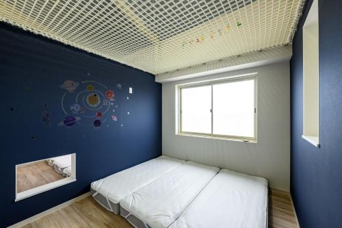 1 dormitorio con 1 cama con pared azul en 子どもがおもいっきり楽しめる一軒家　taiza child, en Kyotango