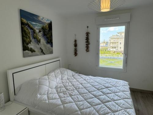 une chambre avec un lit blanc et une fenêtre dans l'établissement Charmant 2P avec balcon, proche plage et centre | Parking | Wifi | 4 pers | Cabourg - FR-1-487-365, à Cabourg