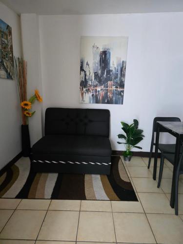 ein schwarzes Sofa in einem Zimmer mit einem Tisch in der Unterkunft 75 metros de la embajada americana in San José