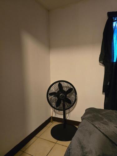 un ventilador negro sentado en una esquina de una habitación en 75 metros de la embajada americana, en San José