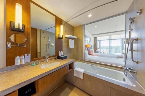 ein Badezimmer mit einer Badewanne und einem großen Spiegel in der Unterkunft Wanda Jin Resort Changbaishan in Baishan
