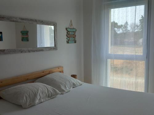 une chambre avec un lit avec un miroir et une fenêtre dans l'établissement Maison neuve 2024, confortable et décorée avec goût, proche plage et forêt, wifi gratuit - FR-1-323-531, à Saint-Jean-de-Monts