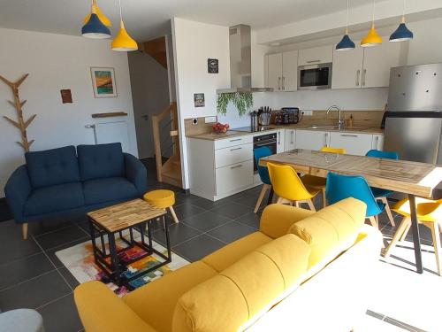 Il dispose d'une cuisine et d'un salon avec un canapé et une table. dans l'établissement Maison neuve 2024, confortable et décorée avec goût, proche plage et forêt, wifi gratuit - FR-1-323-531, à Saint-Jean-de-Monts