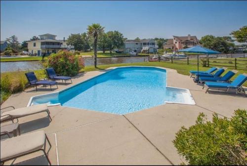 a swimming pool with lounge chairs and a group at Acadian Bay in Virginia Beach