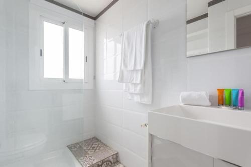 ein weißes Bad mit einem Waschbecken und einem Fenster in der Unterkunft Sunset Boutique Castelldefels by MyRentalHost in Castelldefels