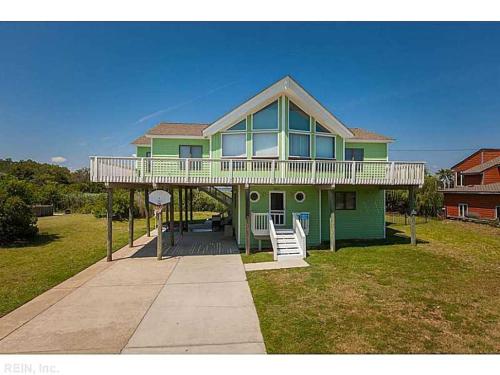 a green house with a porch and a deck at A Free Spirit in Virginia Beach