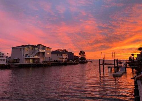 um pôr-do-sol sobre um corpo de água com casas em A Free Spirit em Virginia Beach
