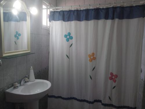 a bathroom with a shower curtain with flowers on it at Caleta del Sur in Las Grutas