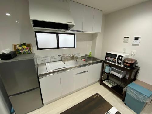 a small kitchen with white cabinets and a sink at Wonderful stay TOKYO nakanoshinbashi in Tokyo