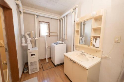a bathroom with a sink and a mirror and a refrigerator at +C FURANO in Furano