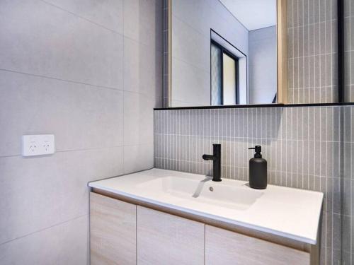 a white bathroom with a sink and a mirror at Benowa 1 Bedroom renovated townhouse in Gold Coast