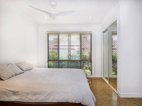 a white bedroom with a bed and a window at Benowa 1 Bedroom renovated townhouse in Gold Coast