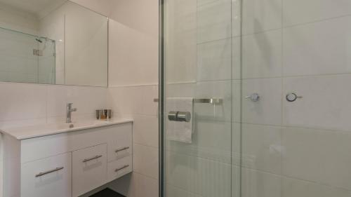 a white bathroom with a shower and a sink at Woodrun in Dinner Plain