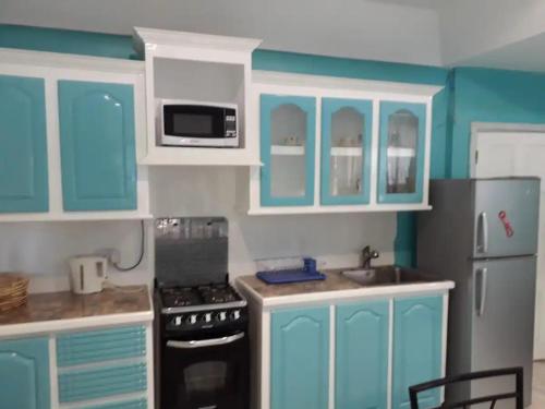 uma cozinha com armários azuis e um fogão e frigorífico em Argalo Suites 2 em Laborie