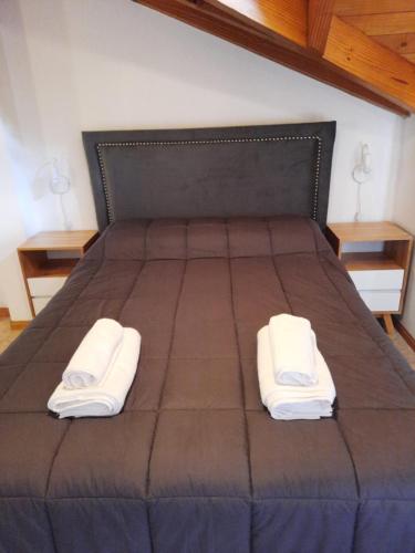 uma cama grande com duas toalhas brancas em Departamento céntrico em San Martín de los Andes