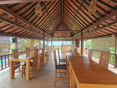 a dining room with wooden tables and chairs at Nusa Sedayu Hotel By Ocean View in Nusa Penida