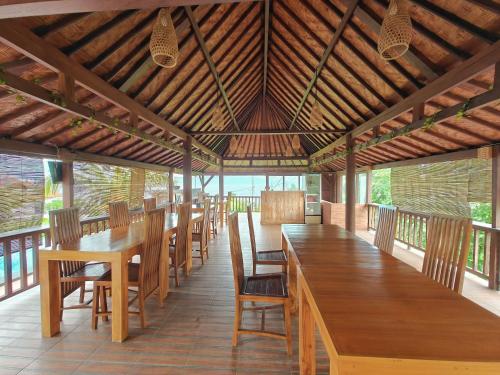 a dining room with wooden tables and chairs at Nusa Sedayu Hotel By Ocean View in Nusa Penida