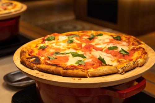 a pizza sitting on top of a wooden plate at Higashikawa Asahidake Onsen Hotel Bear Monte in Higashikawa