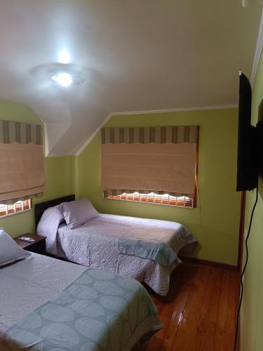 2 Betten in einem Zimmer mit grünen Wänden in der Unterkunft HOSTAL EL VALLE in Angol