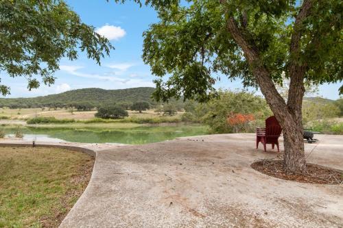a park bench under a tree next to a lake at Indian Springs Lakehouse in Bandera