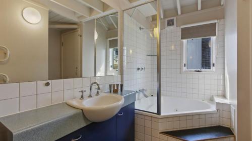uma casa de banho com um lavatório, uma banheira e um espelho. em 1-8 Hot Plate em Mount Hotham