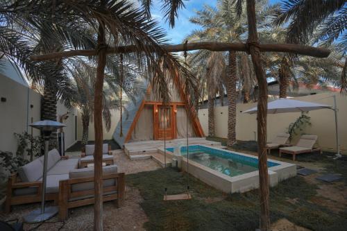 a resort with a swimming pool and palm trees at شاليه ايفالو in Al Hofuf
