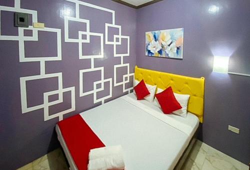 a bedroom with a bed with red and yellow pillows at RedDoorz at Queens Hometel in Tagum
