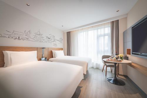 um quarto de hotel com duas camas e uma televisão em UrCove by HYATT Nanjing Downtown em Nanquim