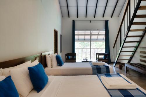 a bedroom with two beds with blue and white pillows at Lario Resort Sigiriya in Sigiriya