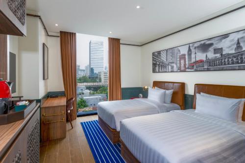 a hotel room with two beds and a television at Ashley Tugu Tani Menteng in Jakarta