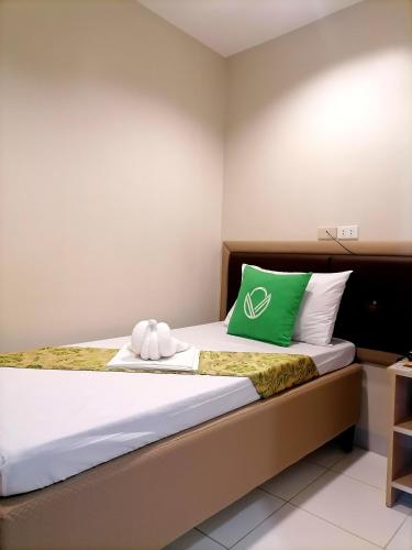 a bedroom with a bed with a green pillow at Airport Poddotel Inc. in Manila